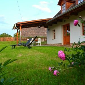ein Haus mit einem Hof mit rosa Blumen in der Unterkunft Bogáncs Vendégház - Nagybörzsöny in Nagybörzsöny