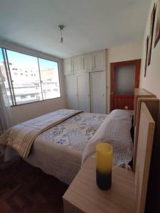 Elegante Apartamento en La Paz في لاباز: غرفة نوم بسرير وشمعة صفراء على طاولة