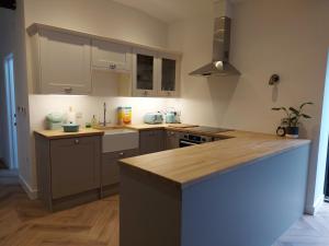 a kitchen with white cabinets and a wooden counter top at Manor Farm Holiday Cottages in Chard