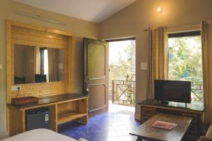 un salon avec une télévision et une grande fenêtre dans l'établissement Swiss Cottage and Spa by Salvus, à Rishikesh