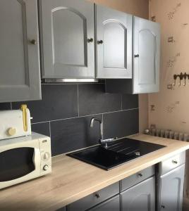 a kitchen with white cabinets and a sink and a microwave at Maison confortable près de la plage de Châtelaillon in Châtelaillon-Plage