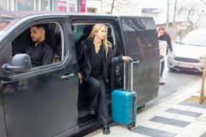 a woman is getting out of a van with a suitcase at Premium Dem Hotel - Istanbul Airport in Arnavutköy