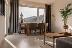 a living room with a dining room table and a large window at Apartment Schwarzwald Panorama in Baden-Baden