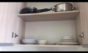 a shelf with plates and bowls and a pot on it at Condo units in Mabolo Garden Flats Cebu in Cebu City
