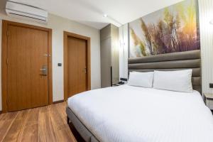 a bedroom with a white bed and a painting on the wall at Dem Premium Hotel - Round Trip Airport Service - Istanbul International Airport in Arnavutköy
