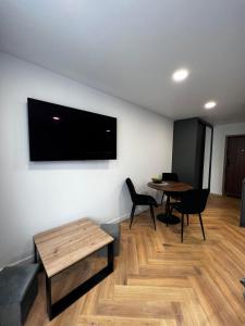 ein Wohnzimmer mit einem Tisch und einem TV an der Wand in der Unterkunft Hygge Apartments in Druskininkai