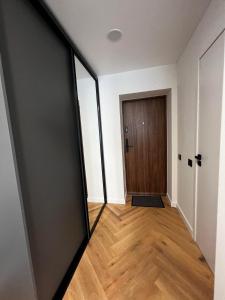 ein leeres Zimmer mit einer Tür und einem Holzboden in der Unterkunft Hygge Apartments in Druskininkai