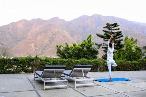 a woman doing a yoga pose in front of two chairs at Swiss Cottage and Spa by Salvus in Rishīkesh