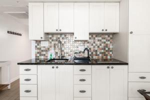 Una cocina con gabinetes blancos y un fregadero. en Oceanfront King Bed 1st Floor Amazing Views, en Pawleys Island