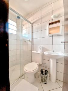 a white bathroom with a toilet and a sink at Água Doce Praia Hotel in Ubatuba
