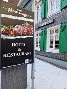 un letrero para un hotel y un restaurante frente a un edificio en Hotel zum Postwagen en Gevelsberg