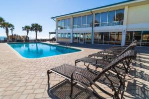 a group of benches next to a building with a pool at Bright Modern Room First Floor Resort View in Pawleys Island