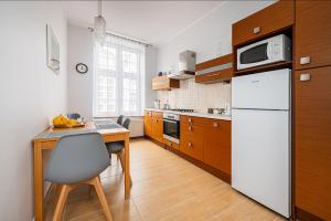 a kitchen with a table and a white refrigerator at Neptun - BillBerry Apartments in Gdańsk