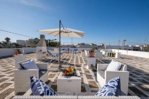 eine Terrasse mit weißen Stühlen und einem Sonnenschirm in der Unterkunft Room in Holiday house - Relais Torre Chianca With Climate, Parking, Wi-Fi Panoramic Rooftop in Porto Cesareo