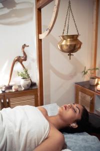 a woman laying on a bed in a bedroom at Swiss Cottage and Spa by Salvus in Rishīkesh