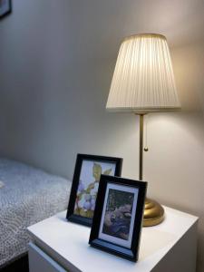 a table with two pictures and a lamp on it at HALBY rooms Rondo ONZ in Warsaw
