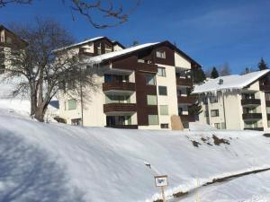 un aparcamiento cubierto de nieve frente a un edificio en Casa Splendusa - sonnige Wohnung in Brigels en Brigels