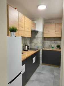 a kitchen with wooden cabinets and a white refrigerator at HALBY rooms Rondo ONZ in Warsaw