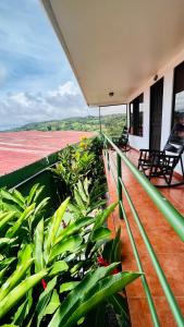 a balcony of a house with chairs and plants at Hostal Nuevo Arenal downtown, private rooms with bathroom in Nuevo Arenal