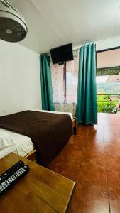 a hotel room with a bed and a table and a television at Hostal Nuevo Arenal downtown, private rooms with bathroom in Nuevo Arenal