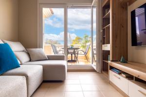 uma sala de estar com um sofá, uma televisão e uma varanda em SUNSET HOLIDAY RIUMAR em Riumar
