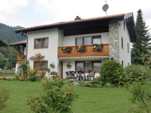 a large white house with a balcony and chairs at Ferienwohnung Deininger inkl. Chiemgaukarte in Ruhpolding