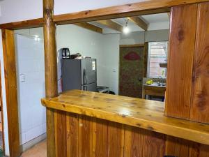 eine Küche mit einer Holztheke und einem Kühlschrank in der Unterkunft Cabaña en San Jose de Maipo in Melocotón
