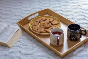 a tray with cookies and a cup of coffee and a book at Grand Studio Le Modern Jungle - Résidence Les Jacquiers in Saint-Denis