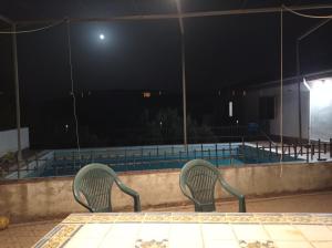 two chairs sitting next to a swimming pool at night at Chalet Venta del Aire in Lanjarón