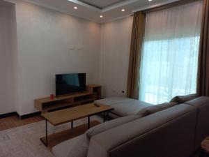 MENBi's Apartment في Kitimē: غرفة معيشة مع أريكة وتلفزيون بشاشة مسطحة