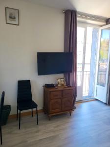 a living room with a tv and a chair and a dresser at Appartement confortable à La Bourboule, 64 m², balcons agréables in La Bourboule