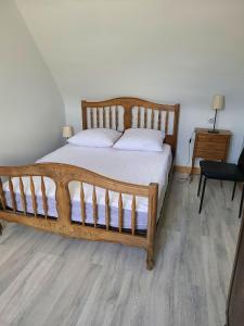 een slaapkamer met een groot houten bed met witte kussens bij Appartement de 2 chambres avec vue sur la ville jardin clos et wifi a La Bourboule a 5 km des pistes in La Bourboule