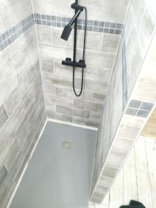 a shower in a bathroom with gray tiles at Appartement confortable à La Bourboule, 64 m², balcons agréables in La Bourboule +7 photos