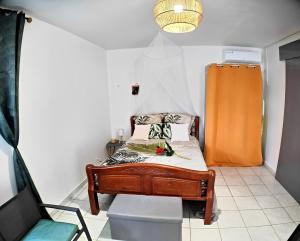 - une petite chambre avec un lit et une chaise dans l'établissement Couleurs caraïbes - Plage et Tranquillité, à Sainte-Anne