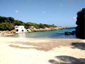 a beach with a white building and the water at Bungalow 4 Binisafua in Binisafua