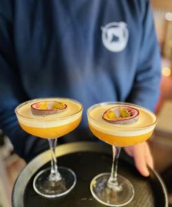 a man standing behind two cocktails on a tray at The Greyhound Inn in Dorchester