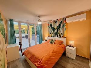 a bedroom with a bed with orange sheets and a window at Casa De Sol Family Home Near Rincon & Beach in Aguada