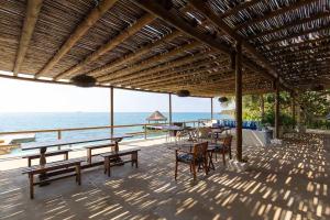 un patio con mesas y sillas y el océano en Wonderful House Paradise in the Rosario Islands, en Cartagena de Indias