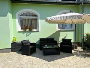 a patio with chairs and an umbrella and a table at Rena Vendégház in Nagykanizsa