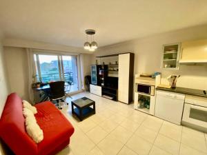 ein Wohnzimmer mit einem roten Sofa und einer Küche in der Unterkunft Nice Ouest St Isidore- 2P au calme in Nizza