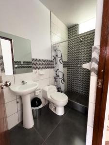 a white bathroom with a sink and a toilet at HOTEL NILA in Cajamarca