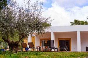 une maison avec des chaises et un arbre en face de celle-ci dans l'établissement Can coll des cocons barefoot house 5min from pacha, à Ibiza