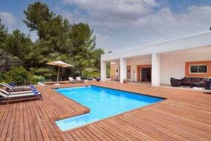 einen Pool auf einer Holzterrasse mit einem Haus in der Unterkunft Can coll des cocons barefoot house 5min from pacha in Ibiza-Stadt