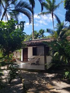 a house with a hammock in front of it at Pousada Pérola do Atlântico in Ilha de Boipeba