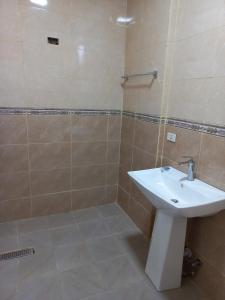 bagno con lavandino bianco e doccia di MENBi's Apartment a Kitimē