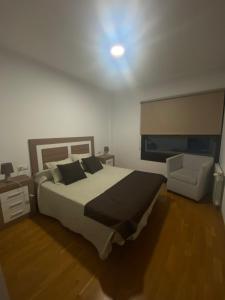 1 dormitorio con 1 cama grande y 1 silla en Playa de Pereiró, en Bueu