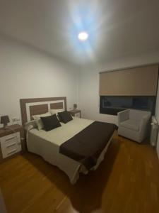 a bedroom with a large bed and a chair at Playa de Pereiró in Bueu