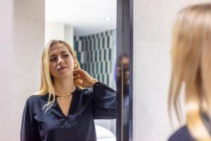 a woman brushing her hair in front of a mirror at Dem Premium Hotel - Round Trip Airport Service - Istanbul International Airport in Arnavutköy