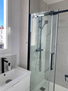 ein weißes Bad mit einer Dusche und einem Waschbecken in der Unterkunft Beau 2 pièces - Mairie de Clichy in Clichy