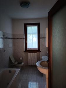 La salle de bains est pourvue d'une baignoire, d'un lavabo et de toilettes. dans l'établissement Signorile quadrilocale nel verde di Villa Guardia, à Villa Guardia